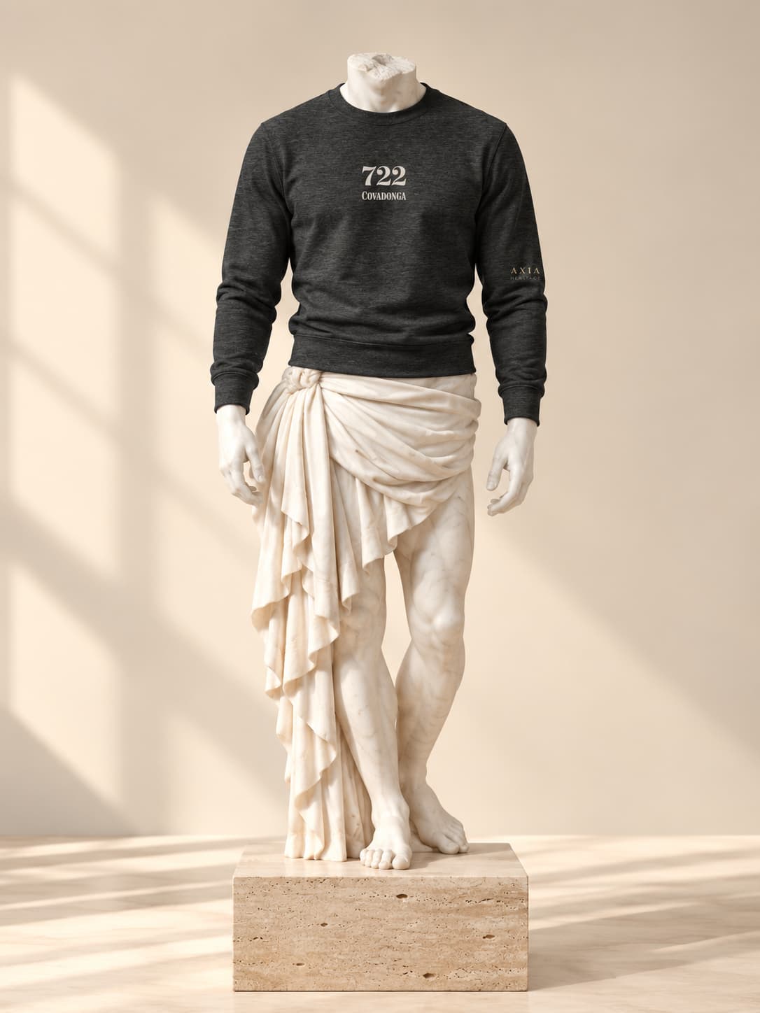 Sudadera Covadonga 722 en gris oscuro, sobre una escultura clásica de mármol, con «722» y «Covadonga» en crema en el pecho